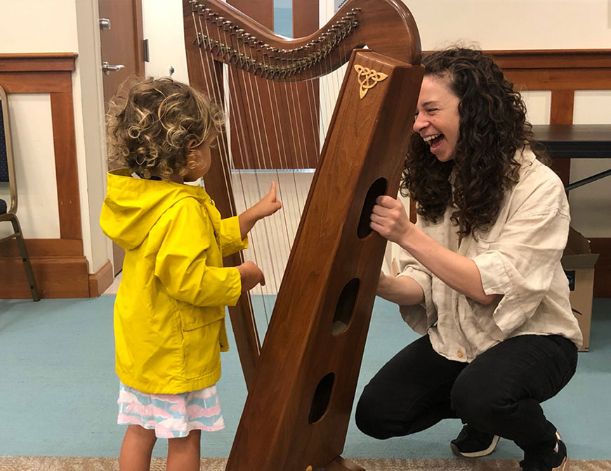 A woman shows a harp to a young child